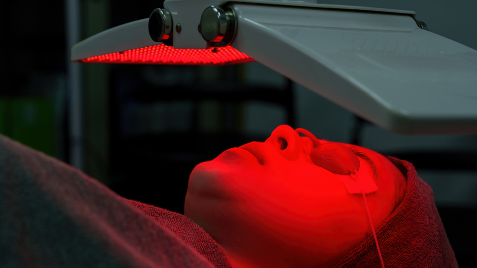 red light being focused over someones face. dr jamie bovay, red light therapy, denver, kinetik chain